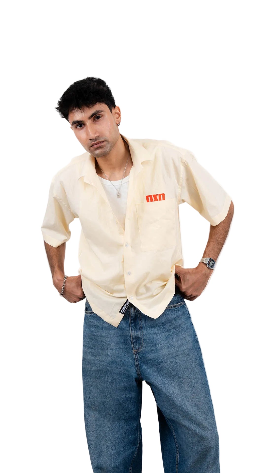 Person wearing a beige shirt with a brand logo and blue jeans on a white background